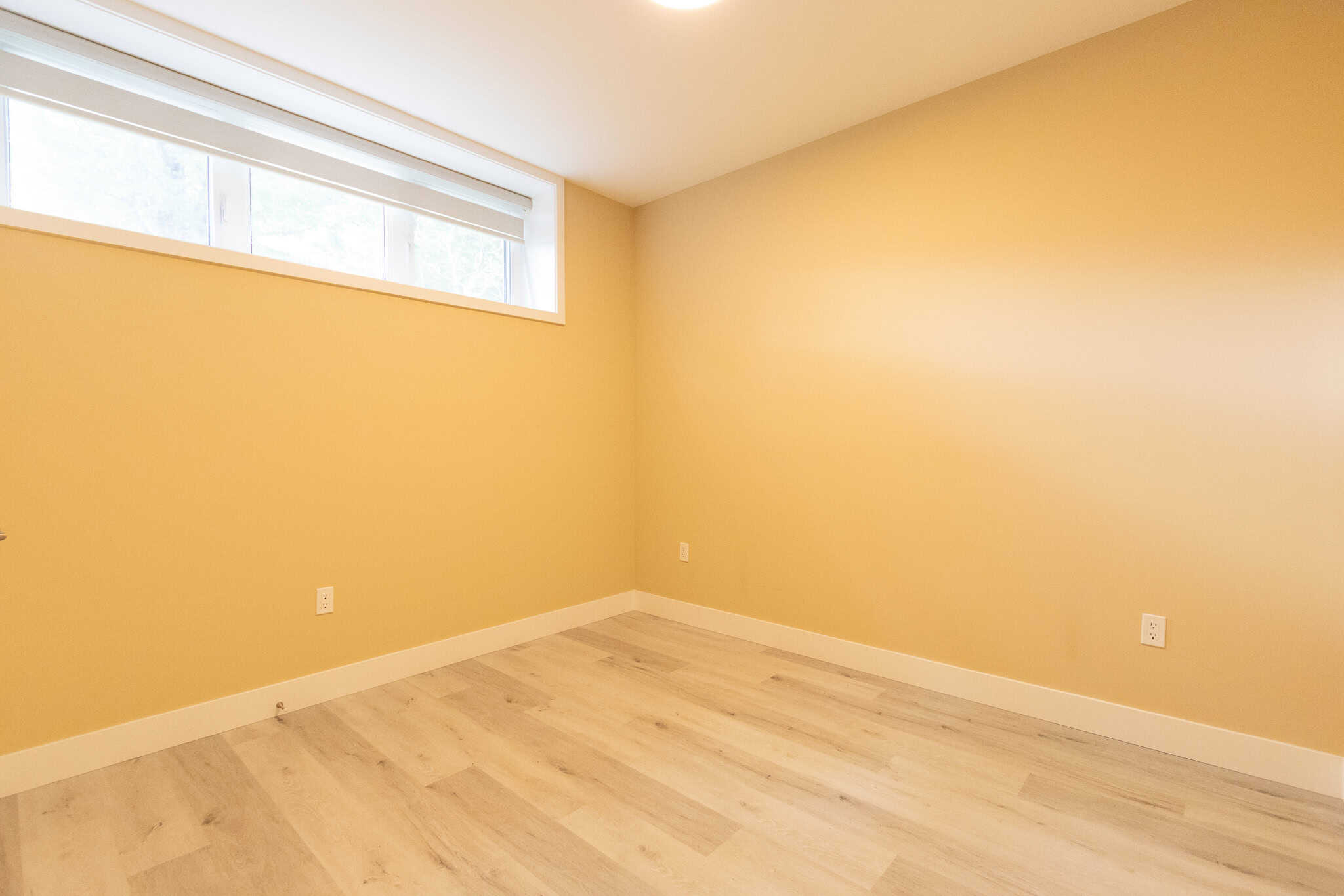 9 Bright empty room with yellow walls, large window, and light wood flooring, ideal for residential real estate or property listing in Vancouver, BC, by Orca Realty Inc.