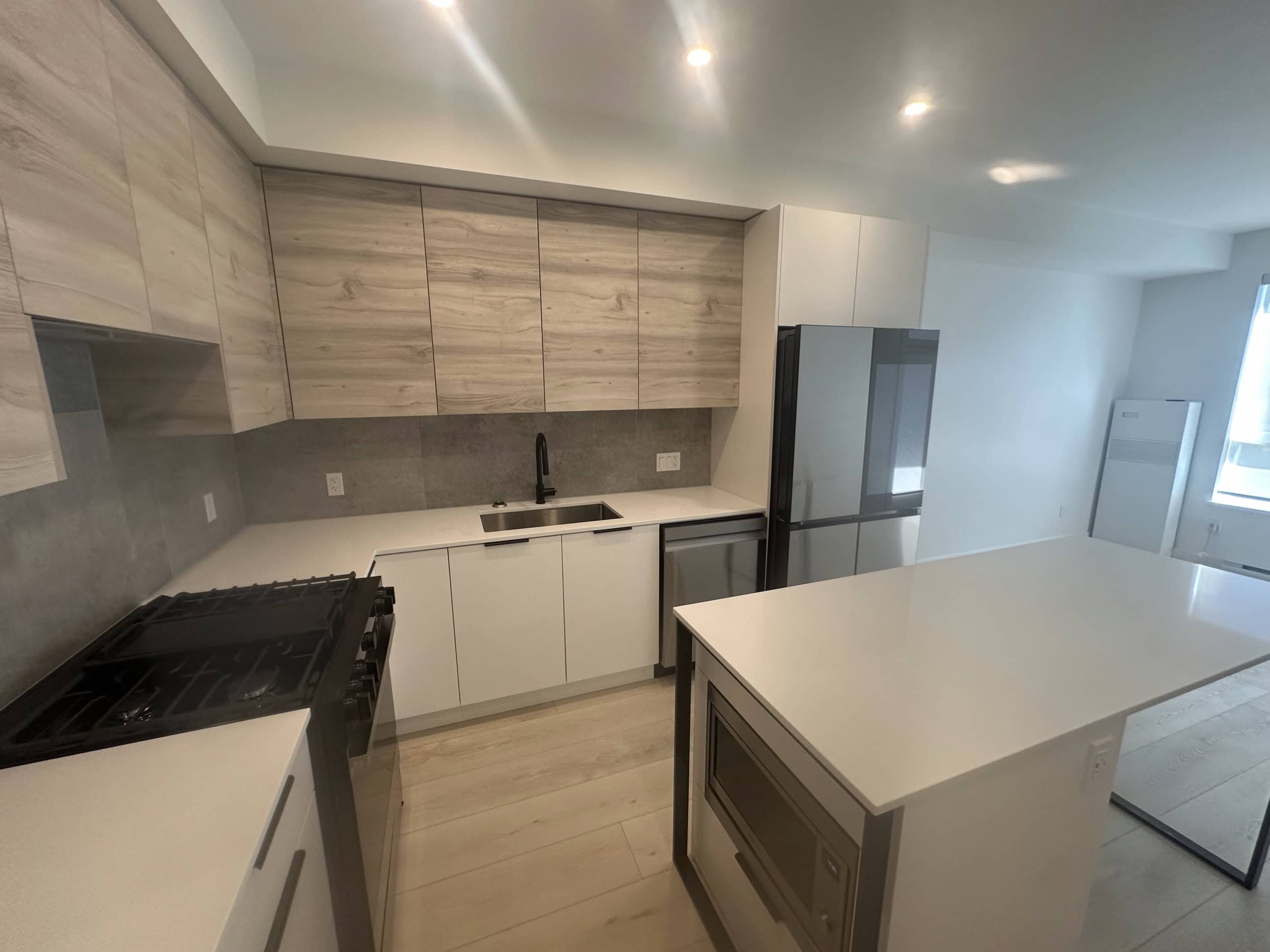 Modern kitchen with sleek white and wood-finish cabinets, stainless steel appliances, and a spacious island, perfect for contemporary Vancouver real estate homes.