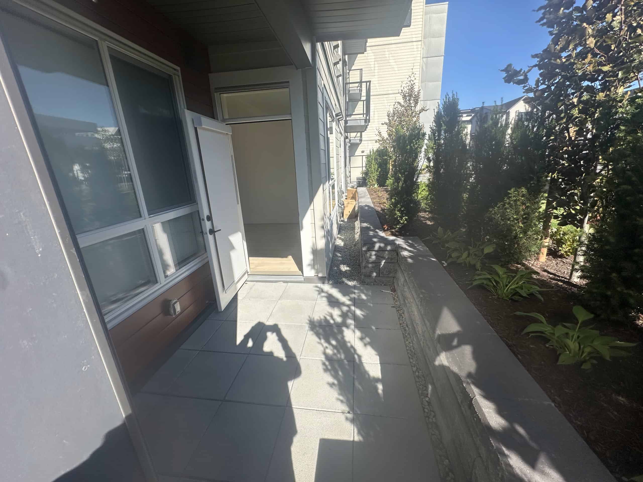 Modern townhouse patio with sliding glass doors and a landscaped garden area, ideal for outdoor living and entertaining in Vancouver, BC.