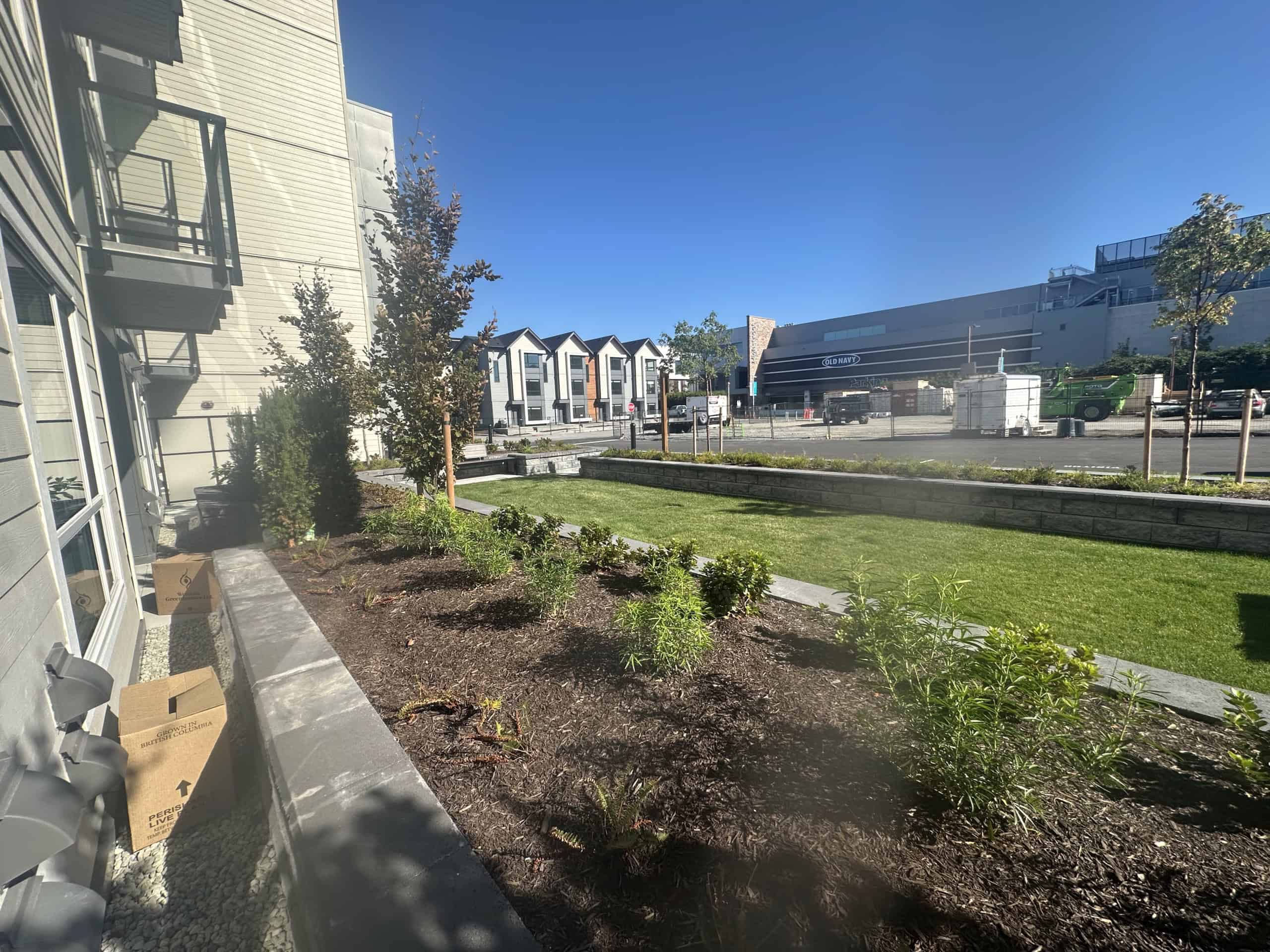 Modern residential building with landscaped garden and parking lot in an urban setting, showcasing Orca Realty Inc.'s expertise in Vancouver-area real estate.