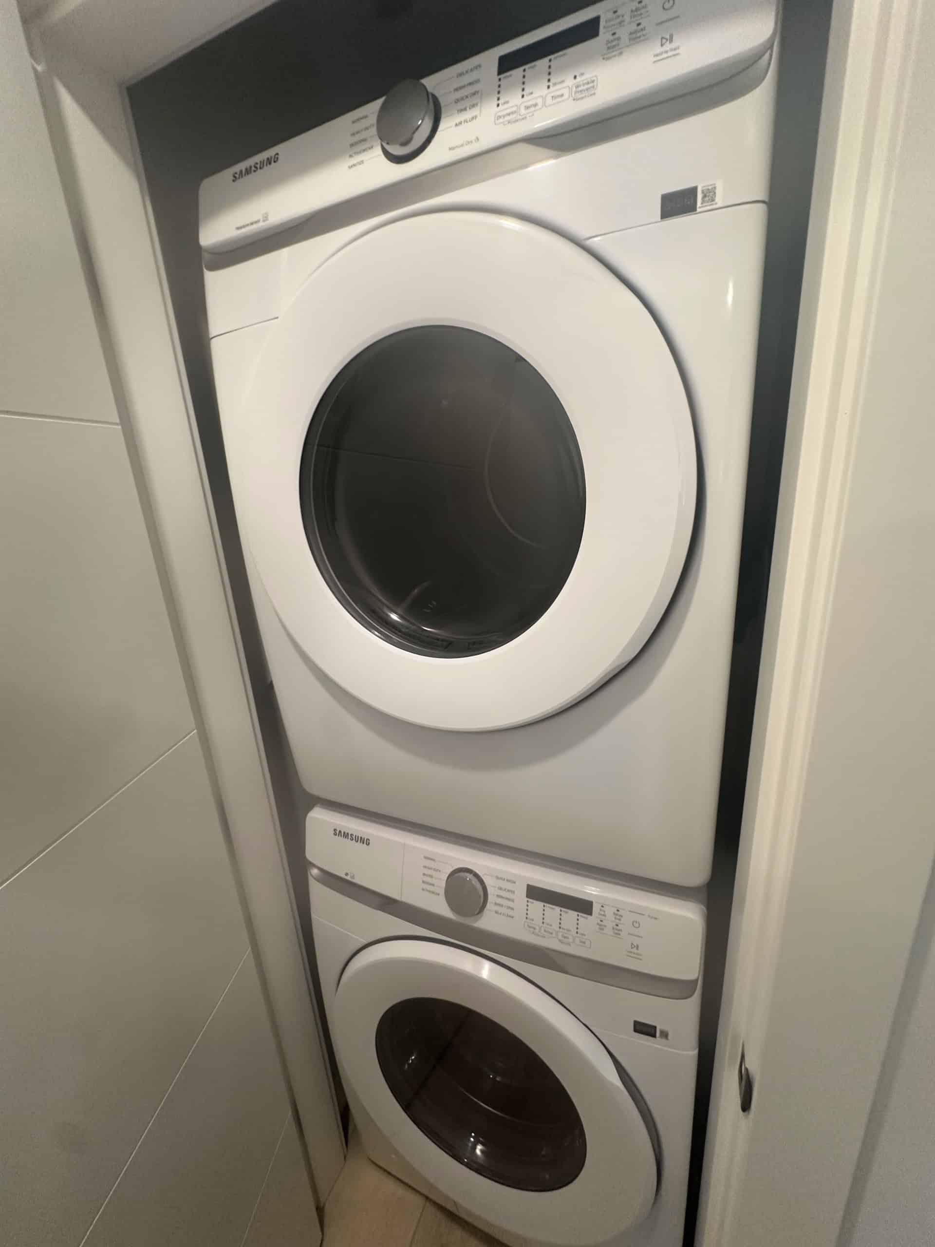 Samsung front-loading washer and dryer stacked in a compact laundry nook. Modern, energy-efficient appliances perfect for small spaces and convenient laundry solutions.