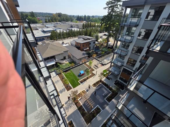 Modern urban apartment courtyard with landscaped gardens, playground, and outdoor seating, surrounded by contemporary residential buildings and city views in Vancouver, BC.