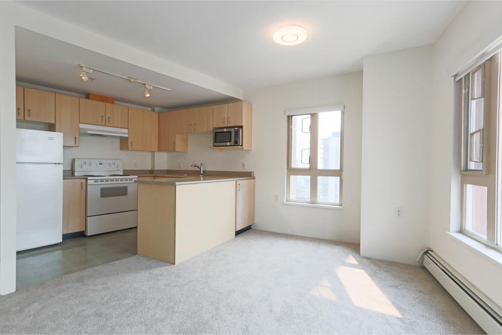 Bright open-concept kitchen and living area in a modern apartment, featuring large windows, natural light, and contemporary appliances for comfortable city living.