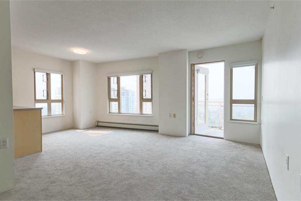 Bright living room in a high-rise apartment with large windows and balcony access, showcasing modern urban living and scenic city views in Orca Realty Inc. listings.