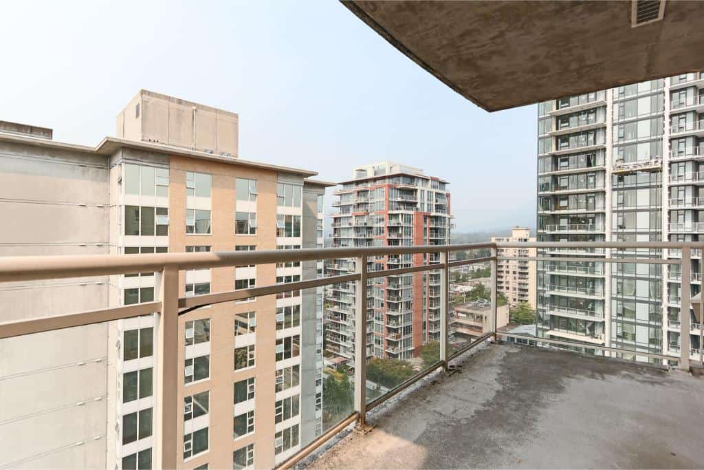 Panoramic view from a high-rise condo balcony in Vancouver, showcasing modern urban residential buildings in a vibrant cityscape.