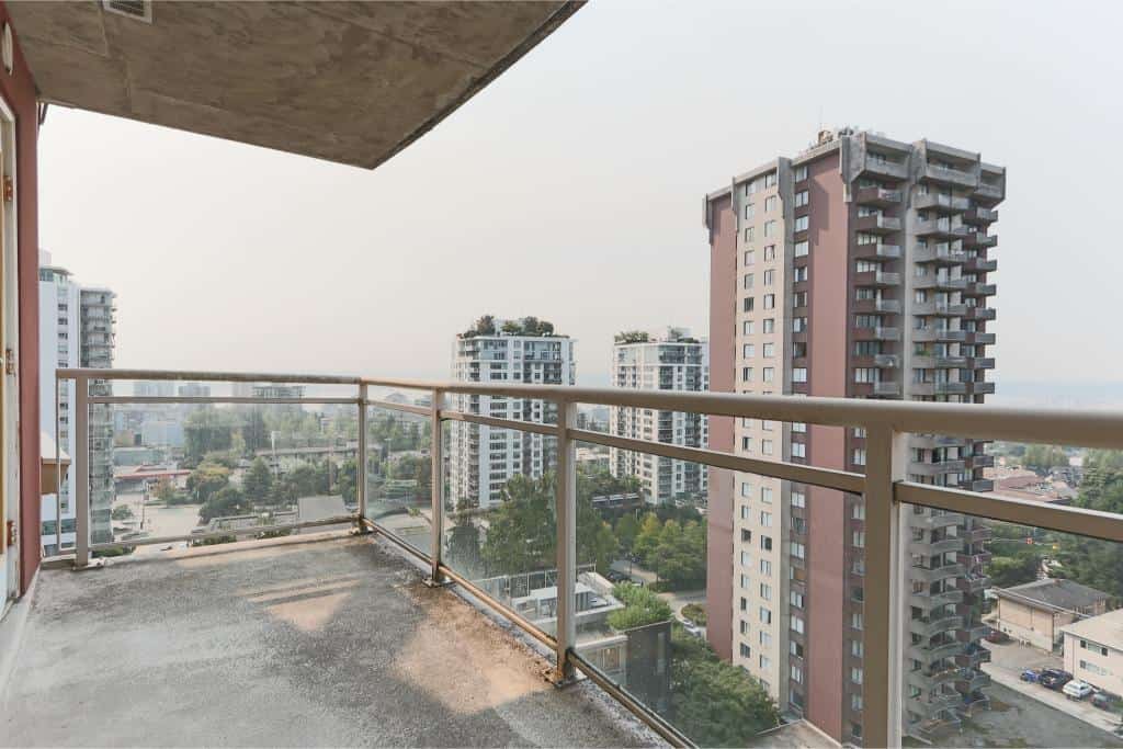 Spacious balcony with city views in Vancouver high-rise condo, featuring modern railings and ample outdoor space, ideal for relaxing or entertaining.