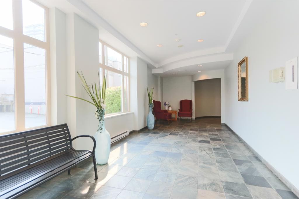 Bright modern lobby interior with large windows, stylish vases, and comfortable seating, showcasing Orca Realty Inc.'s professional real estate office environment.