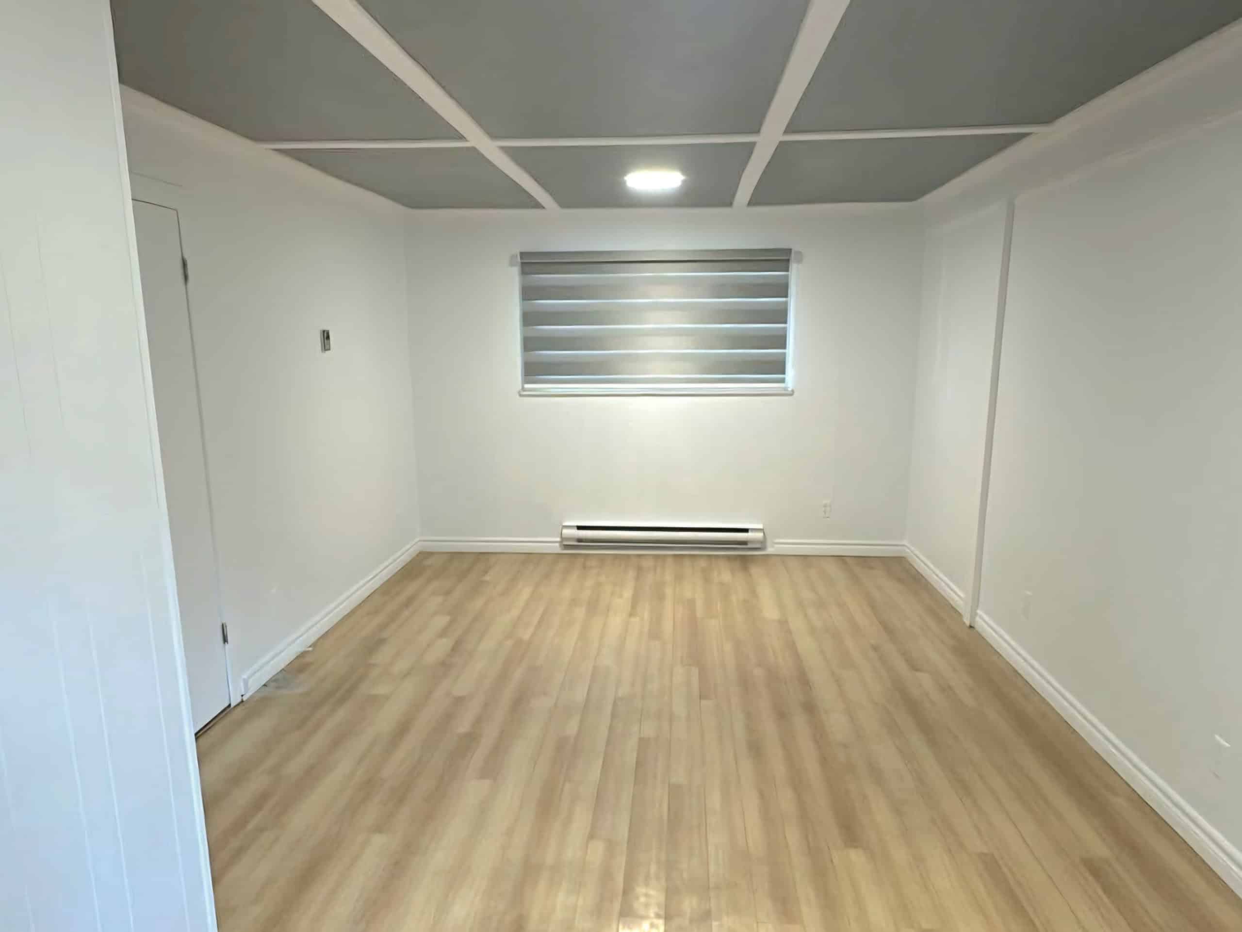 Screenshot_20250923_221543_Facebook Bright empty room with white walls, large window with horizontal blinds, and light wood flooring, perfect for real estate listing in Greater Vancouver and interior home staging.