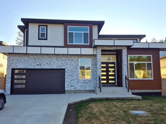 Modern new construction house with contemporary design and stone accents, featuring large windows, a spacious garage, and a stylish front entrance, ideal for Vancouver Island real estate buyers.
