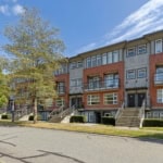 Modern multi-unit residential building in Vancouver with brick and siding exterior, featuring stairs and glass balconies, ideal for real estate investments and renting.