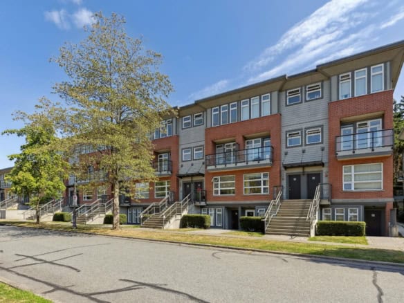 Modern multi-unit residential building in Vancouver with brick and siding exterior, featuring stairs and glass balconies, ideal for real estate investments and renting.