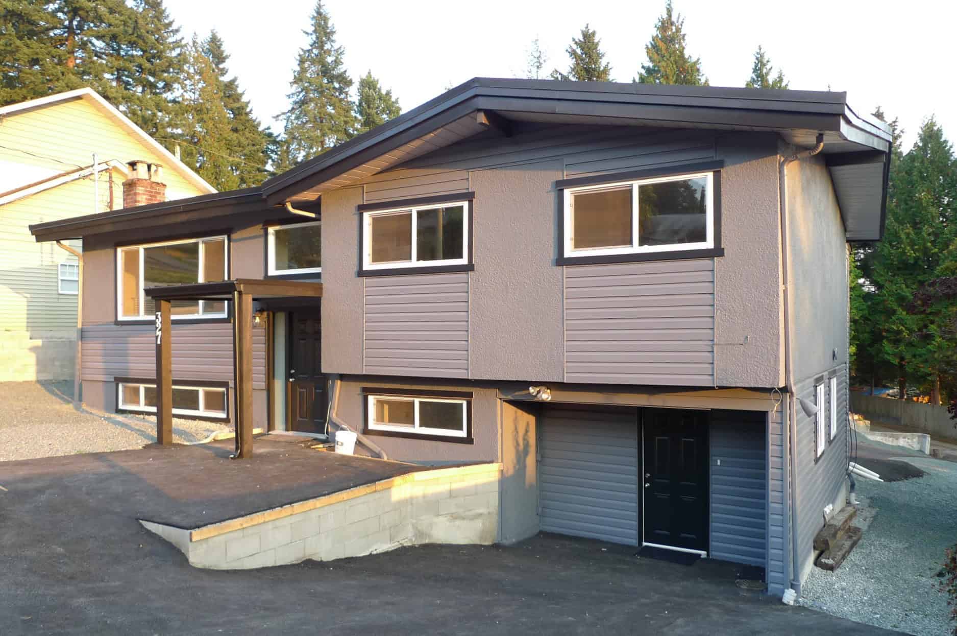 Modern duplex house with gray siding and large windows, situated in a peaceful neighbourhood, perfect for real estate investing or family living in BC.