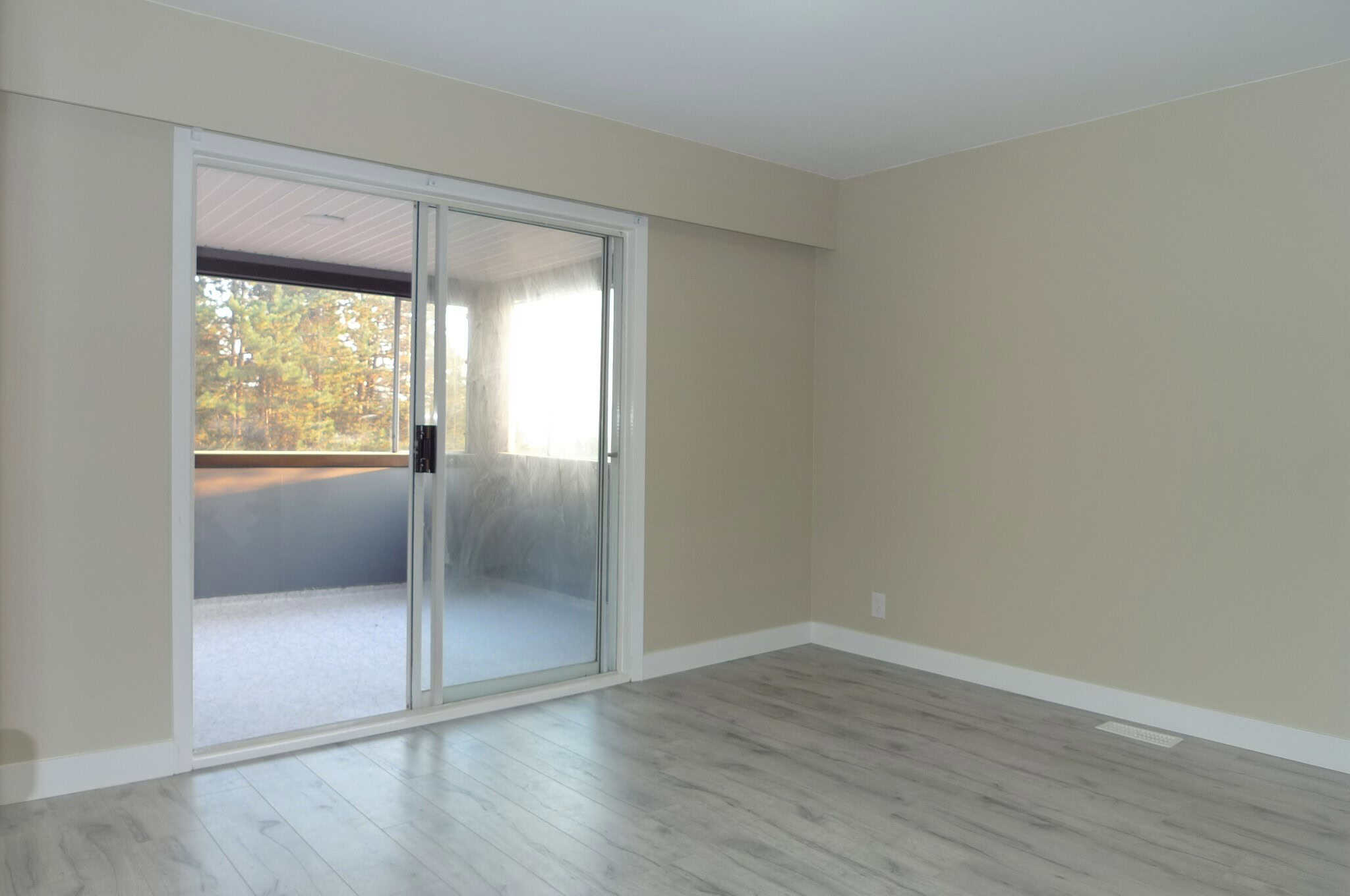 Bright apartment with sliding glass door leading to balcony, new flooring and neutral wall color, ideal for Vancouver property buyers seeking modern interior design.