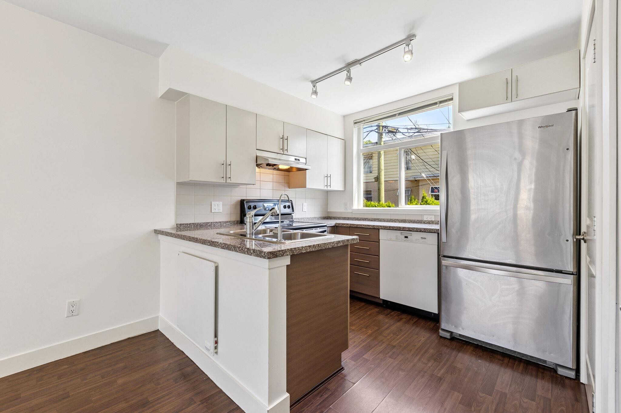 Modern kitchen interior with stainless steel refrigerator and white cabinetry, ideal for Vancouver homes.