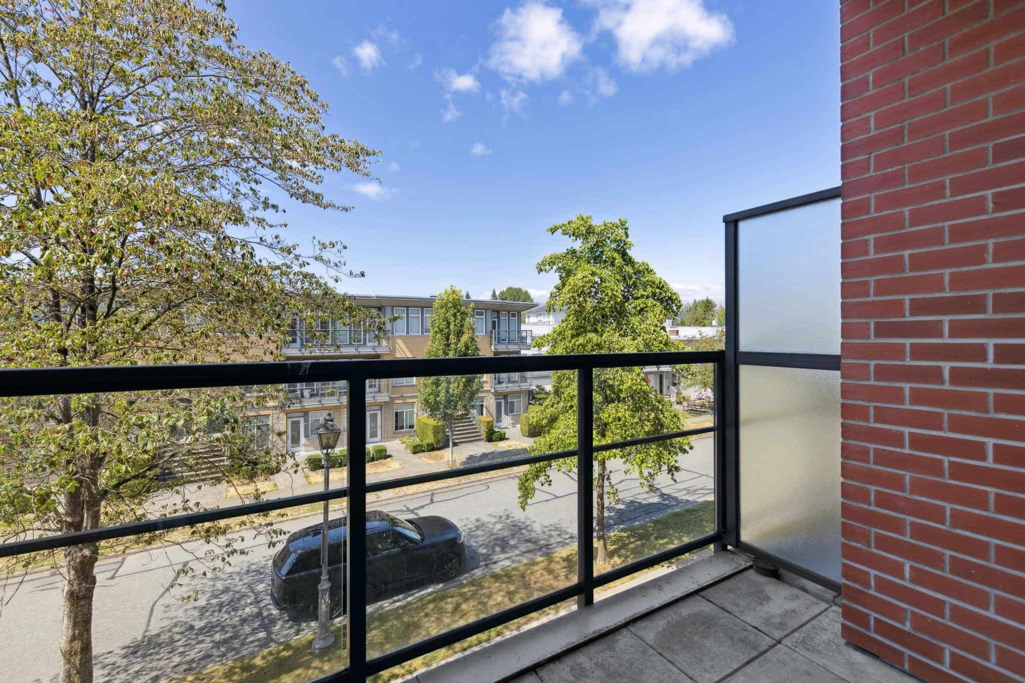 Modern balcony view of tree-lined street and contemporary apartment buildings, highlighting urban living in Vancouver from Orca Realty Inc.