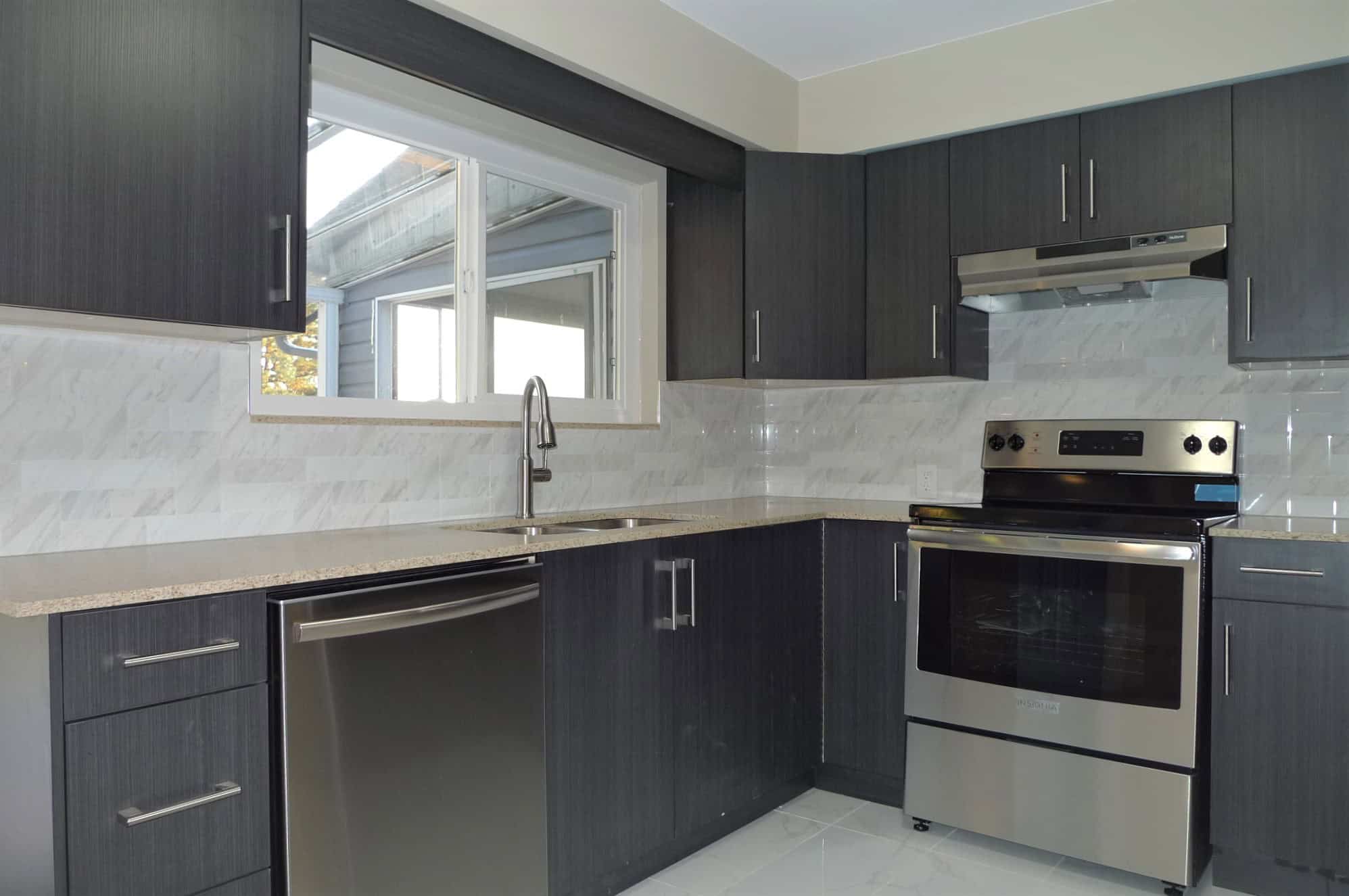 Modern kitchen with dark cabinetry, stainless steel appliances, and a marble backsplash, ideal for Edmonton real estate and homebuying in Alberta.