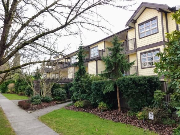 Spacious multi-family residential building with lush landscaping, tall evergreen trees, and welcoming walkways, located in a prime neighbourhood for real estate investment in Vancouver, BC.