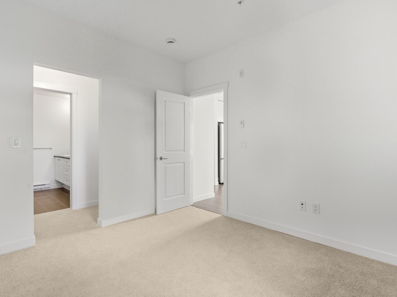 Newly renovated interior of a modern home for sale, showcasing a bright, spacious living room with neutral carpet and white walls, perfect for family living and interior design.