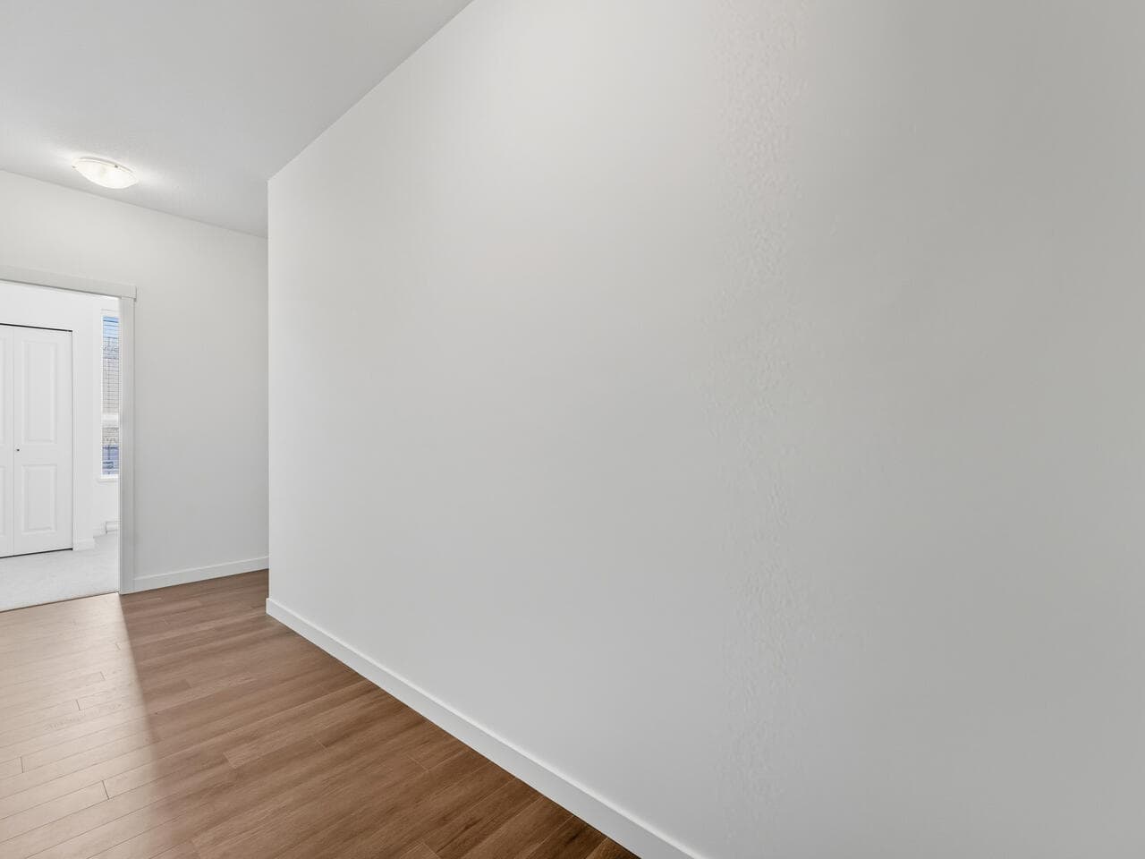 Bright and clean interior space showcasing modern minimalist design with white walls and wooden flooring, ideal for real estate listings with Orca Realty Inc.
