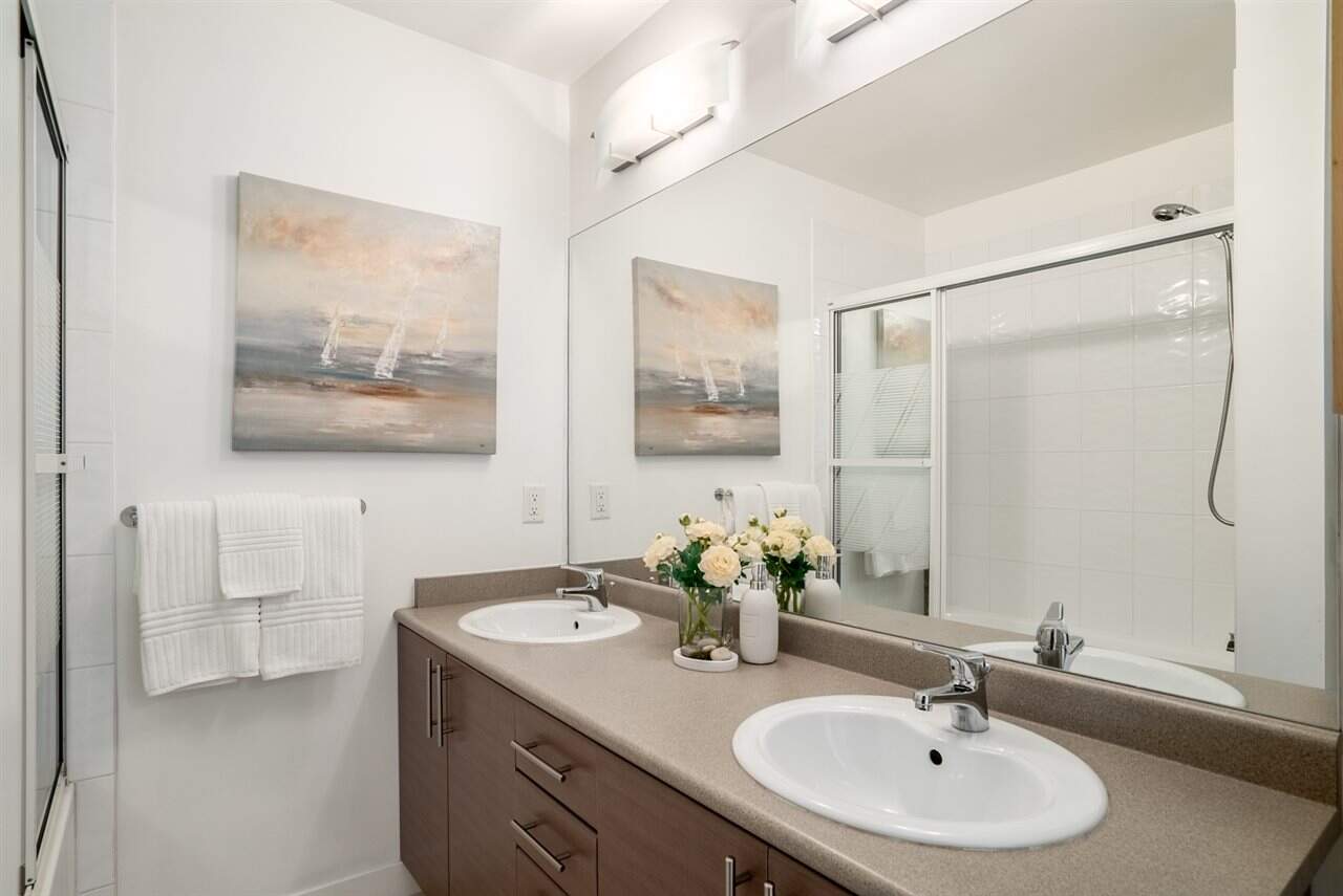 Modern bathroom with dual sinks, neutral countertops, and contemporary decor, ideal for Vancouver and BC real estate listings, featuring elegant fixtures, decor, and a spacious shower.
