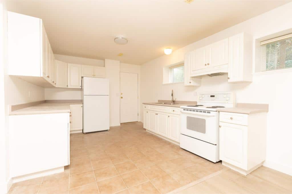 Bright white kitchen with ample cabinet storage and modern appliances, ideal for Vancouver Island real estate.