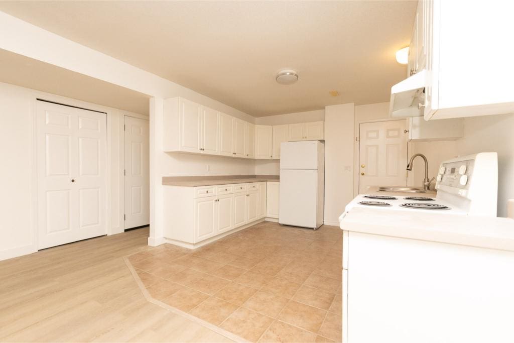 Bright white kitchen with ample cabinet storage, white appliances, and a separate laundry area, ideal for Vancouver Island homes.
