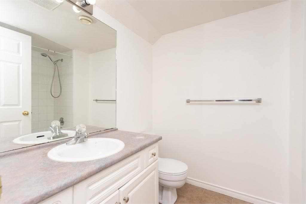 Bright bathroom with white cabinetry and tiled shower, perfect for Calgary homes – Orca Realty Inc.