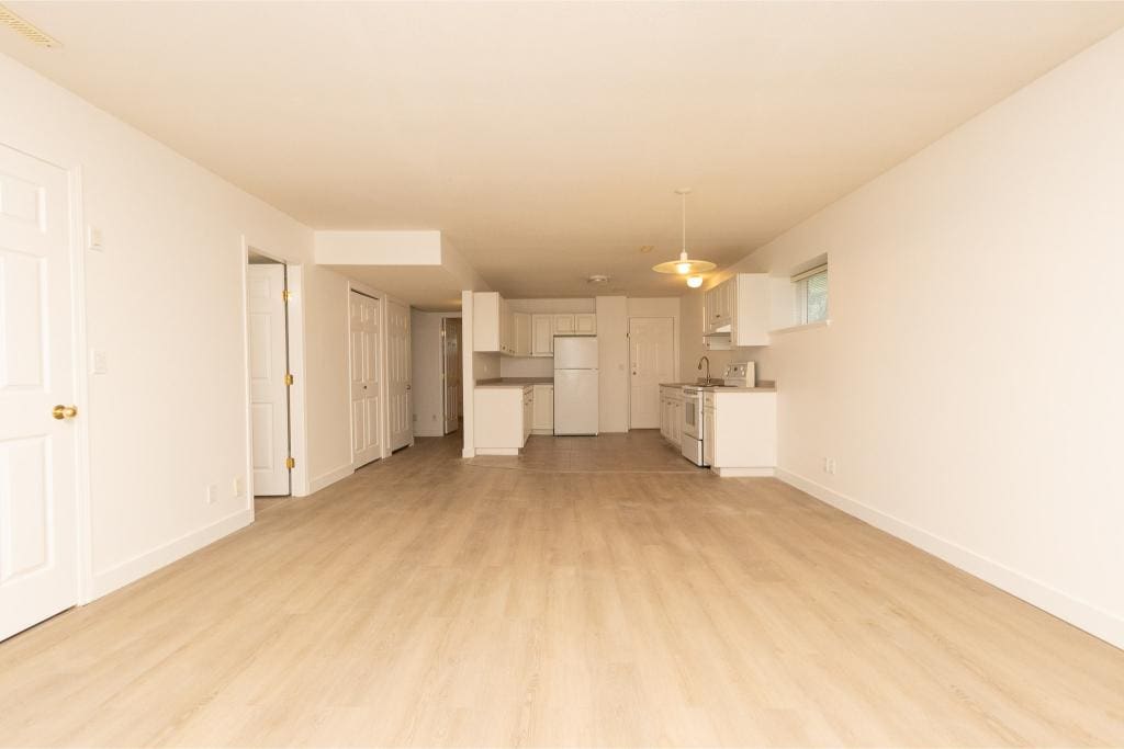 Bright open-concept kitchen and living space with modern white cabinetry, laminate flooring, and ample natural light, perfect for family living or entertaining in BC.
