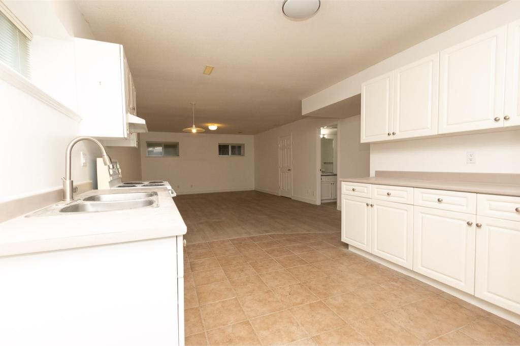 Spacious open-concept kitchen and living area featuring white cabinetry, countertops, and tiled flooring, ideal for family living and entertaining in Orca Realty Inc. listings.