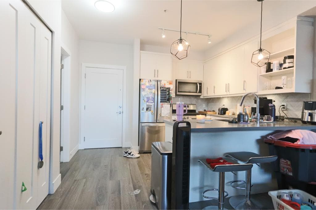 Modern white kitchen with stainless steel appliances and contemporary pendant lighting for Vancouver real estate listings.