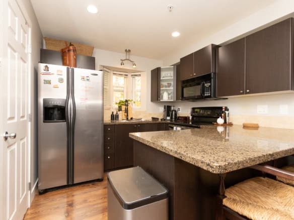 Modern kitchen with dark wood cabinets, granite countertops, stainless steel appliances, and cozy seating area, perfect for Vancouver Island real estate buyers and agents.
