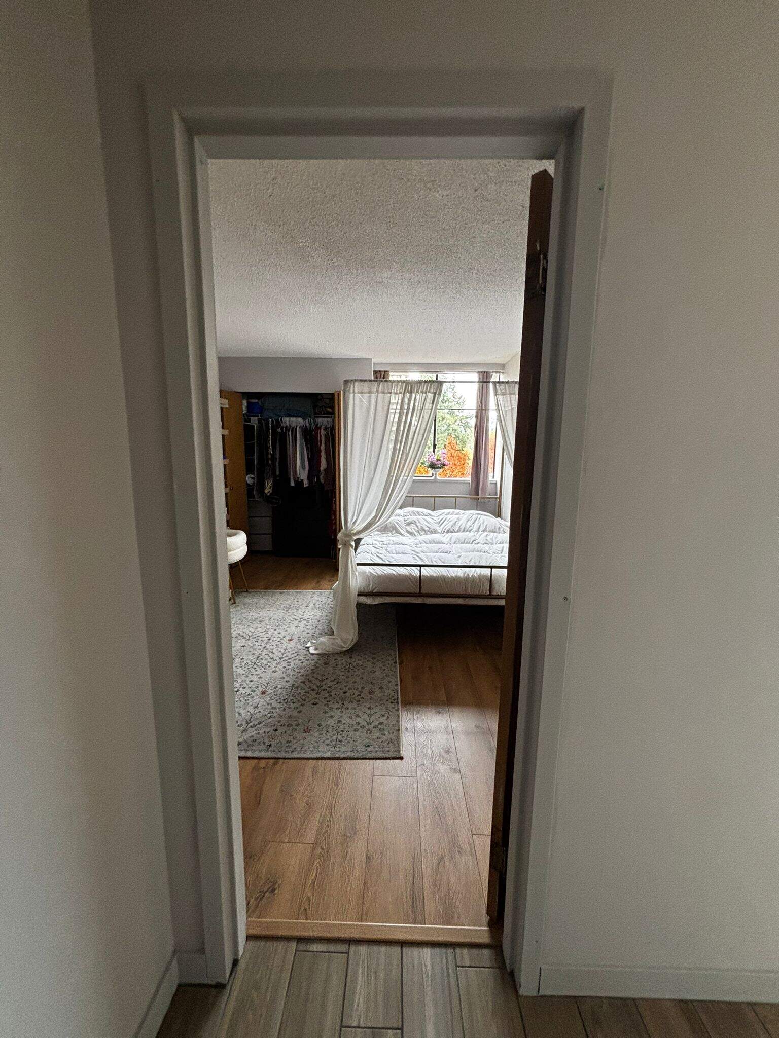 Spacious bedroom interior with open closet and large window showing outdoor scenery, featuring hardwood flooring and natural light, perfect for Vancouver home buyers.
