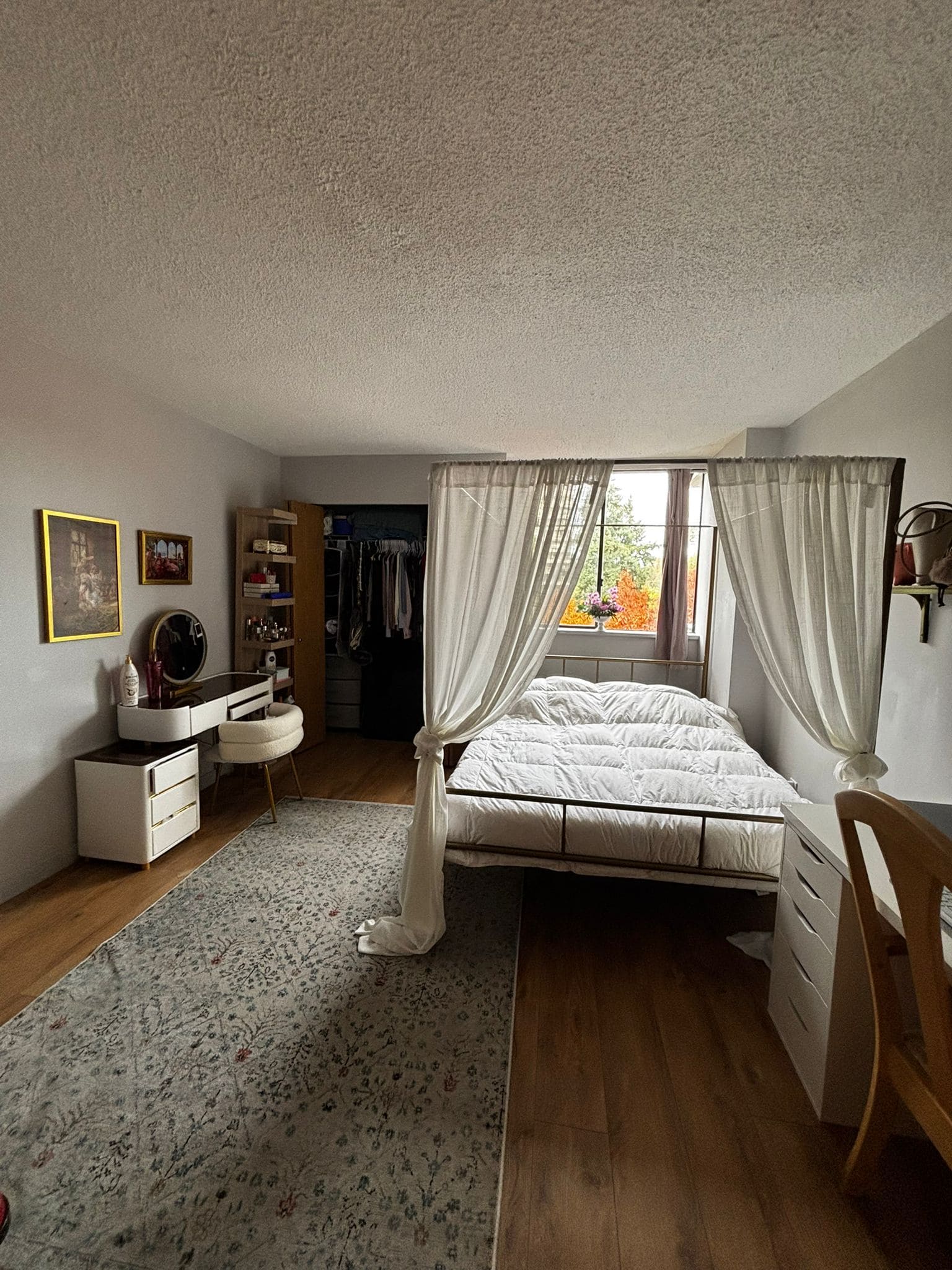 Cozy bedroom with white canopy bed, natural light from window, wooden floors, and stylish decor in a home listed by Orca Realty Inc.