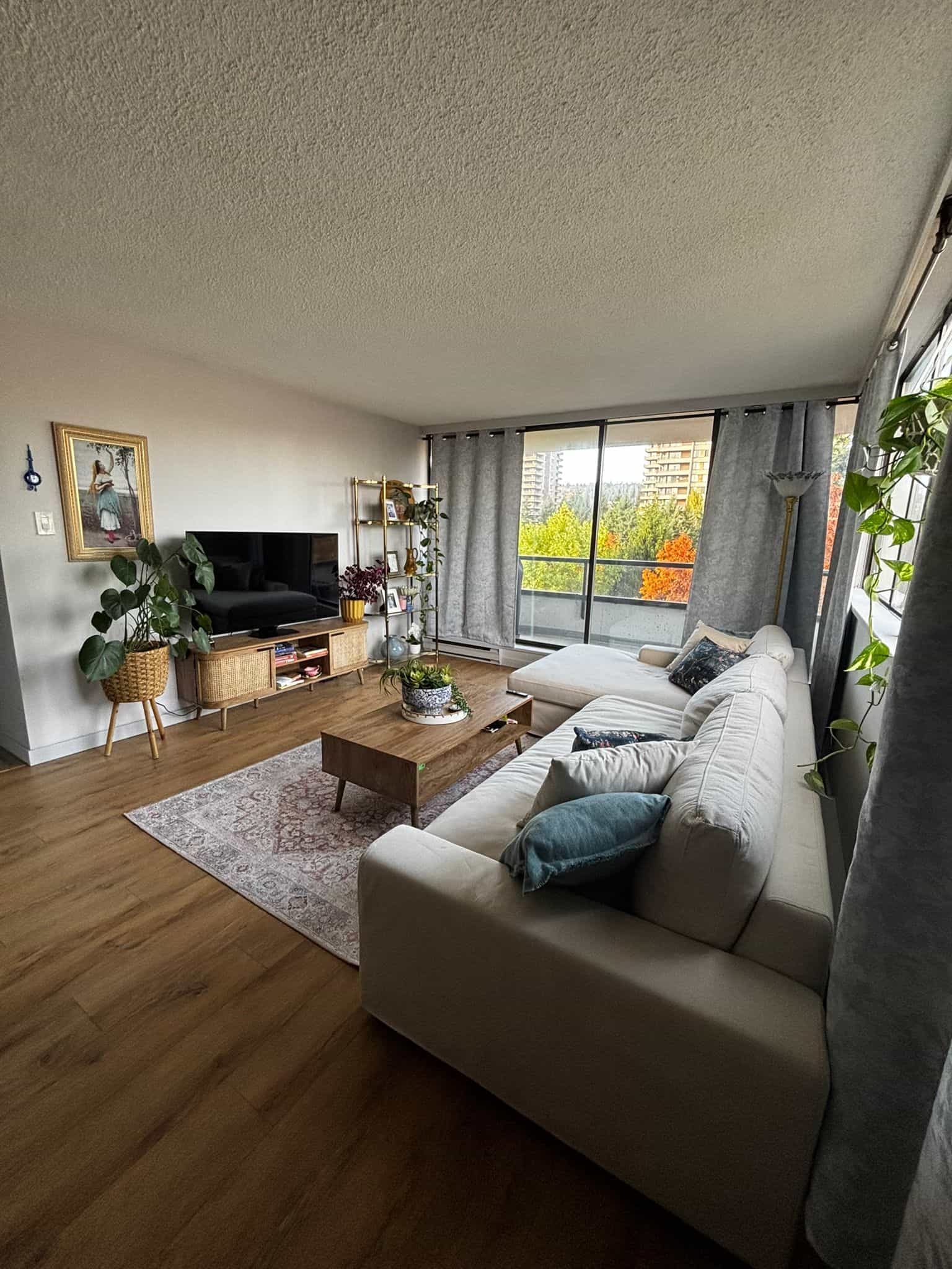 Bright and spacious living room in a Vancouver apartment with large windows offering urban views, cozy sectional sofa, modern decor, and hardwood floors for a stylish, comfortable home by Orca Realty Inc.