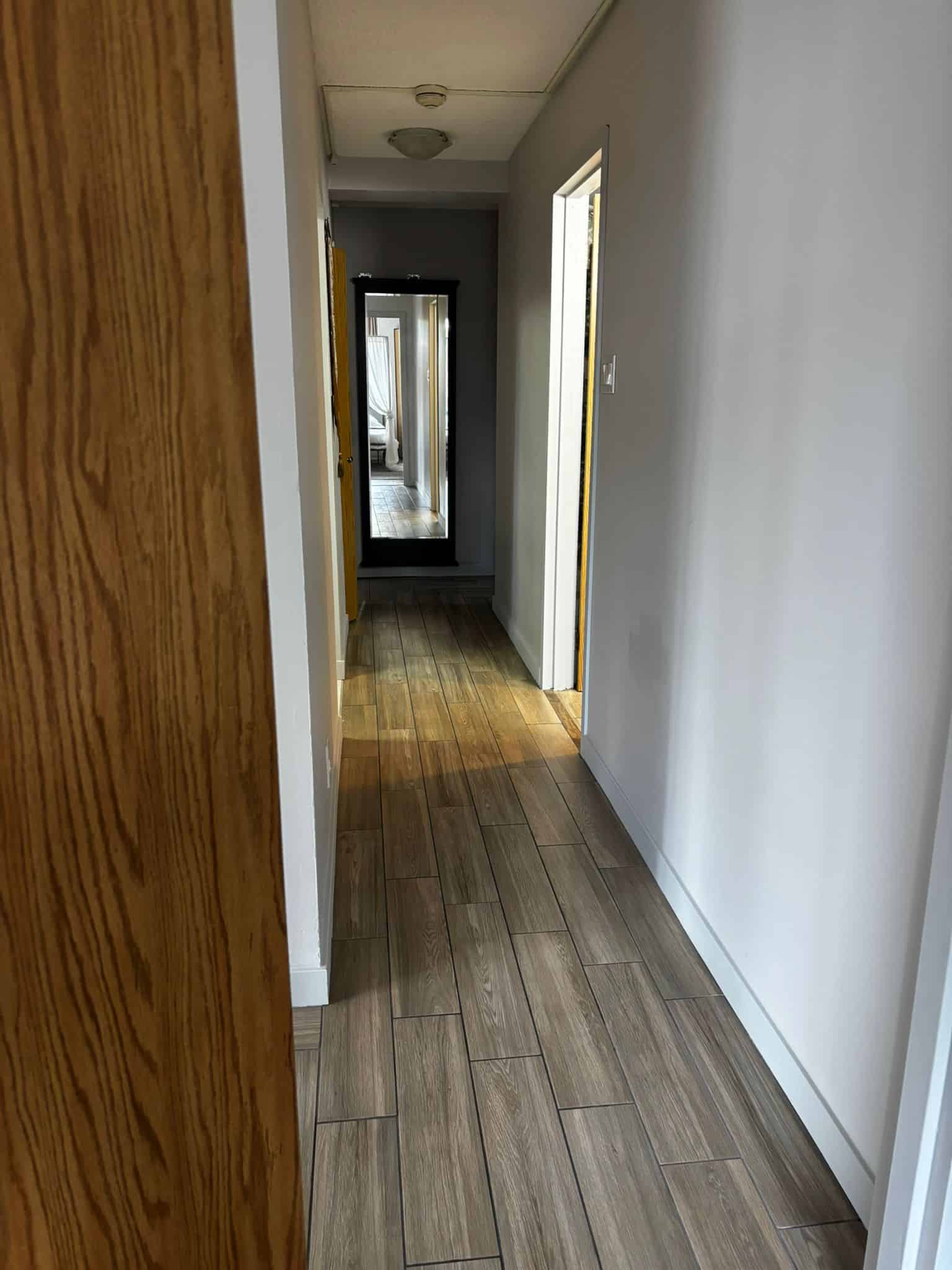 Bright hallway interior in modern condo, showcasing wood-look tile flooring, neutral wall colors, and natural light, ideal for Vancouver property listings.