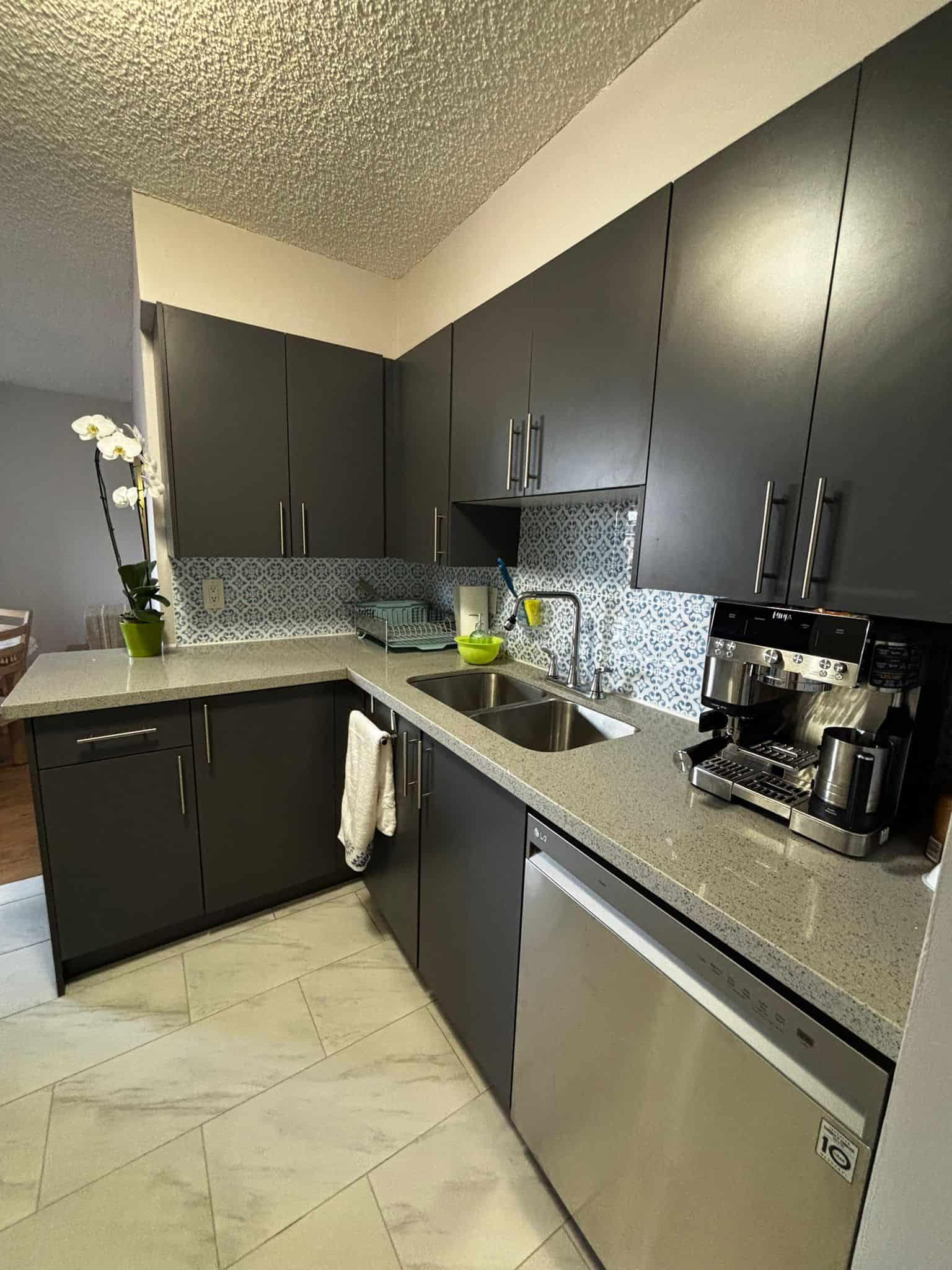 Modern grey kitchen with quartz countertops, stainless steel appliances, and patterned tile backsplash, perfect for Vancouver real estate buyers seeking stylish, functional spaces.