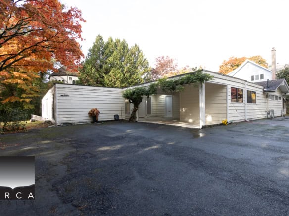 Spacious driveway in front of a modern residential property with white siding, surrounded by colorful autumn trees, showcasing a well-maintained yard and a welcoming exterior for potential buyers.
