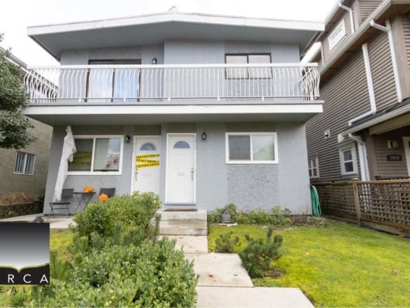 Modern two-storey grey residential home with a front yard, balcony, and new windows, located in a friendly neighbourhood, ideal for Vancouver homebuyers seeking real estate expertise.