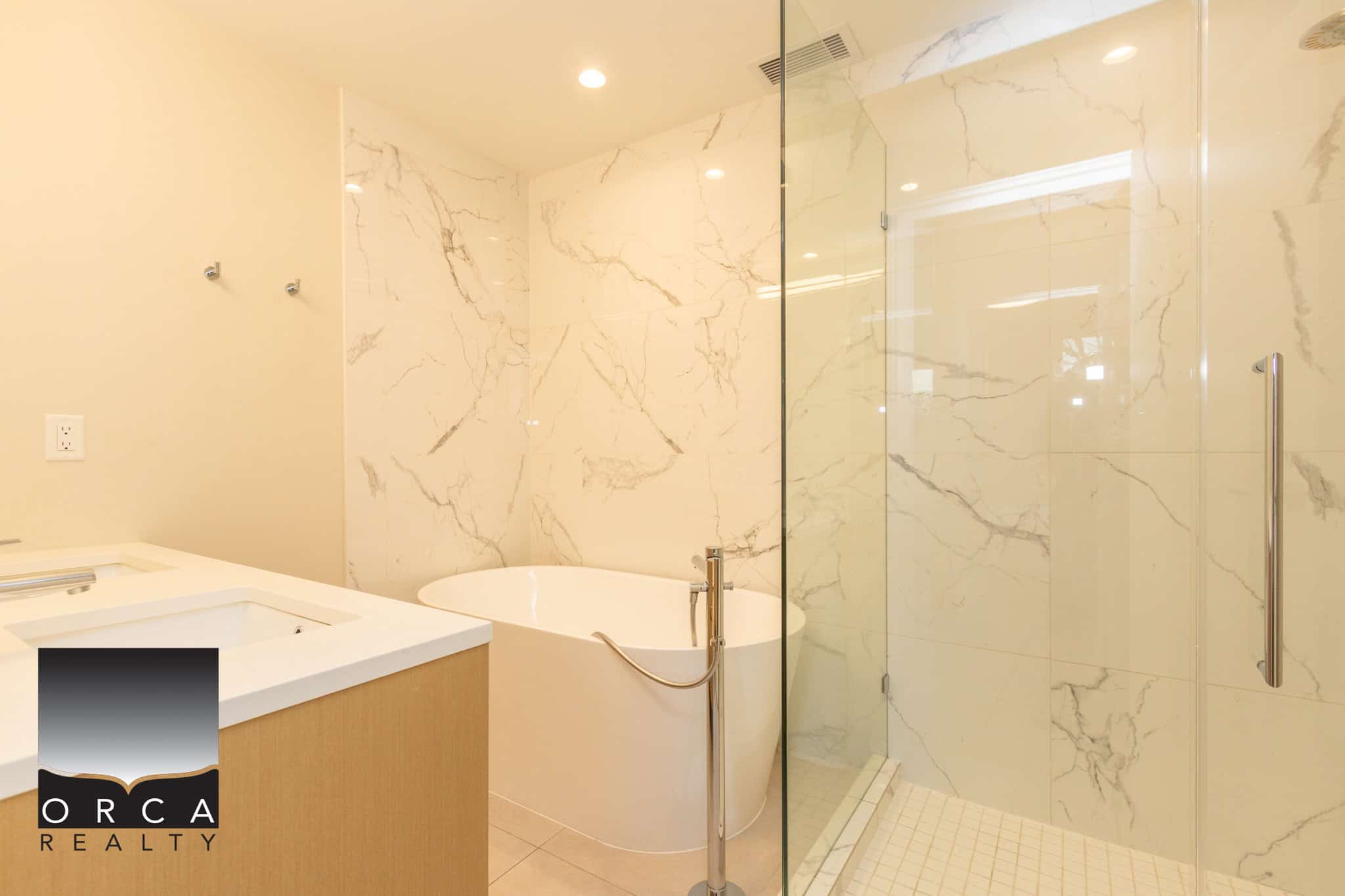 Luxurious bathroom featuring marble walls and a glass shower enclosure in a North Vancouver property listed by Orca Realty Inc.