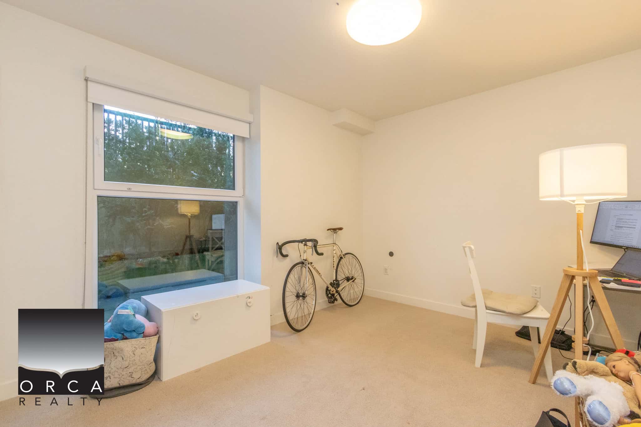 Bright room with large window, bicycle, and workspace.