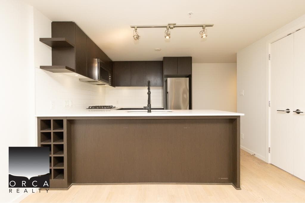 Modern kitchen featuring dark cabinetry, stainless steel appliances, and a white countertop, perfect for Vancouver Island real estate showcasing contemporary design.