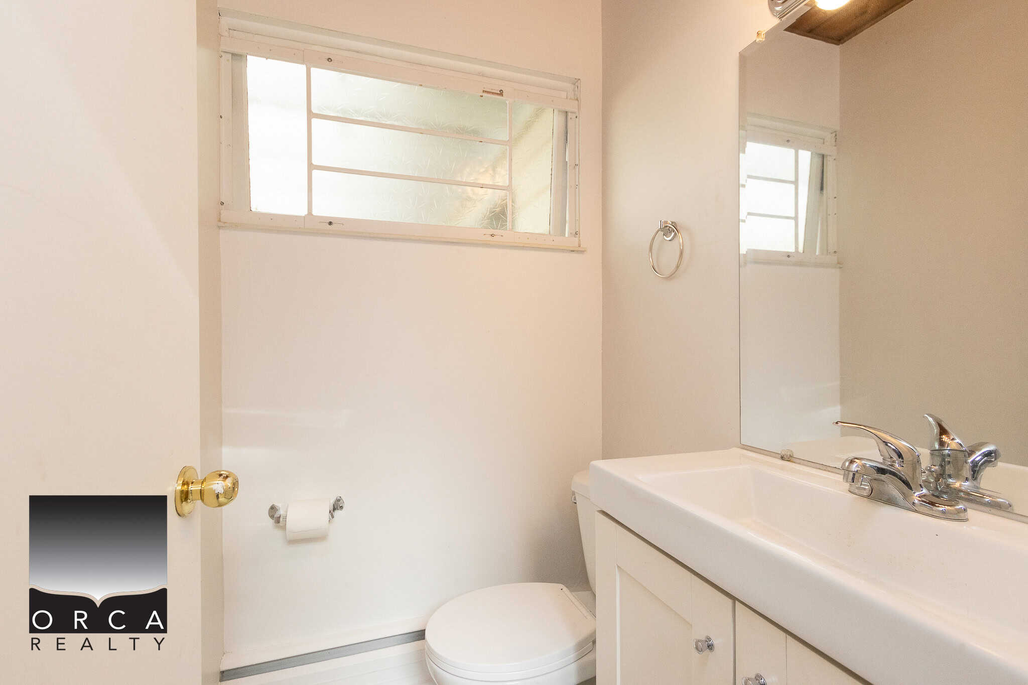 Bright small bathroom with a white sink, mirror, and window, perfect for Vancouver Island home or real estate listings. Managed by Orca Realty Inc., offering expert property services in BC.