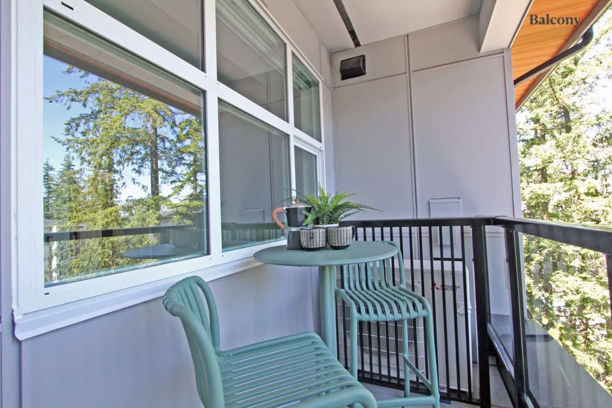 Bright balcony with modern outdoor furniture, lush green trees in the background, and large windows, showcasing the perfect outdoor living space offered by Orca Realty Inc.