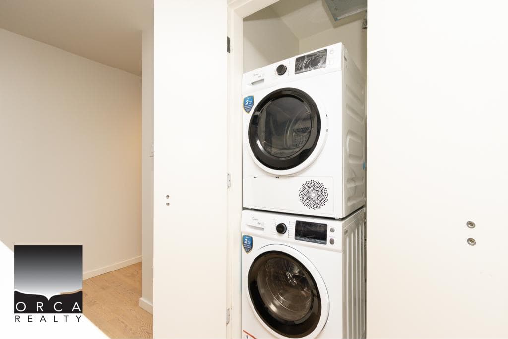 Efficient laundry area with stacked washer and dryer units in a modern home, showcasing convenient utility space in a Calgary property.