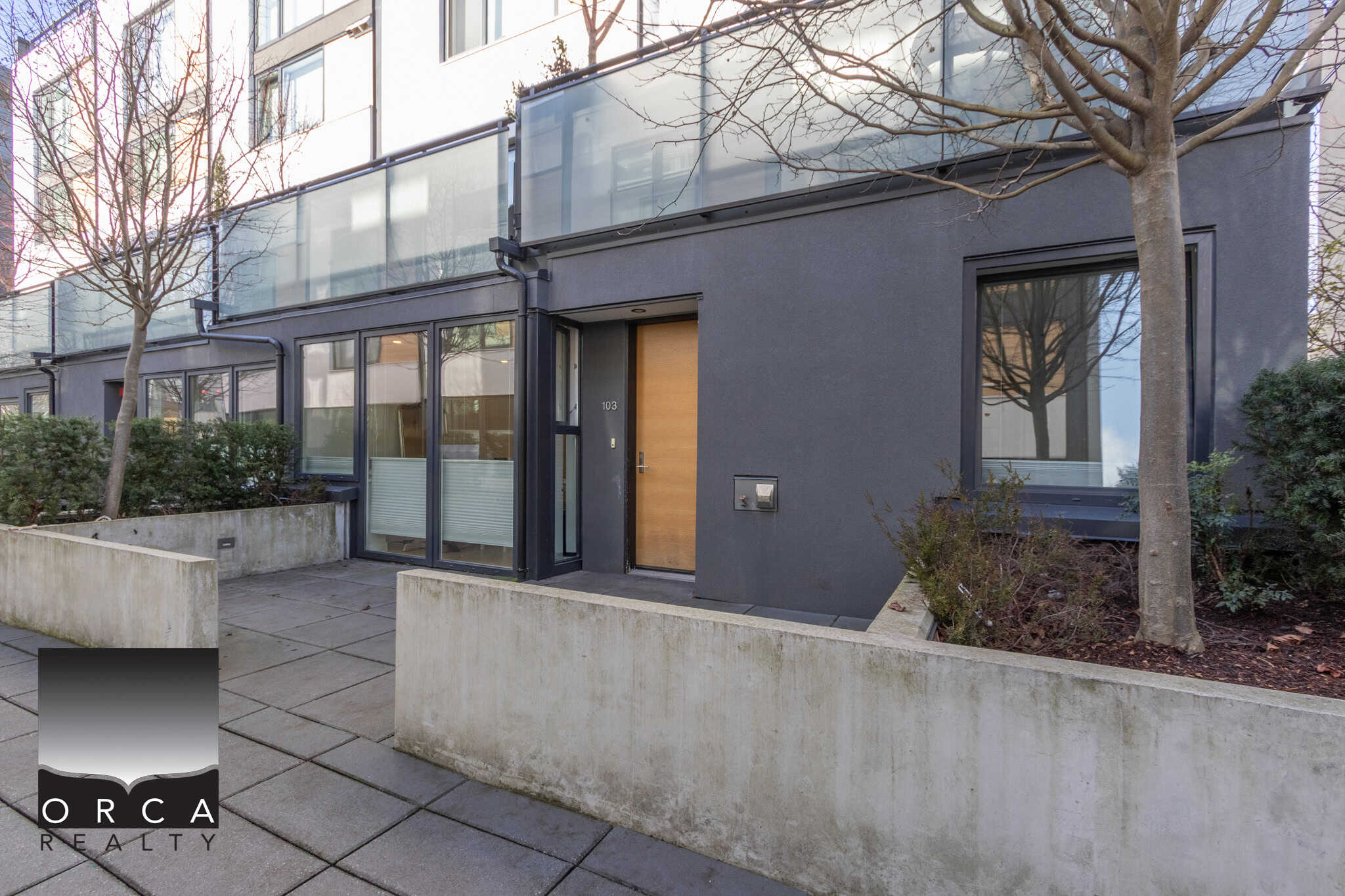 Contemporary condo entrance in North Vancouver with sleek design, large glass windows, and minimalist landscaping, located at 103-649 3rd Street East.