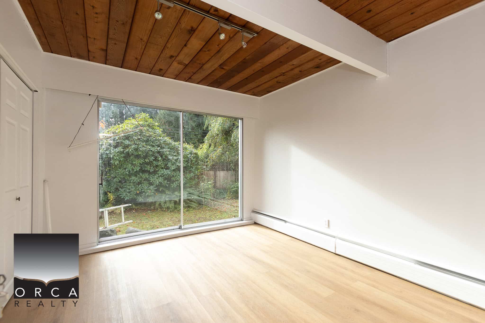 Bright spacious room with large sliding glass door leading to backyard, ideal for real estate showcasing in Vancouver, BC. Modern interior, natural light, hardwood flooring, perfect for homebuyers seeking property in Vancouver.