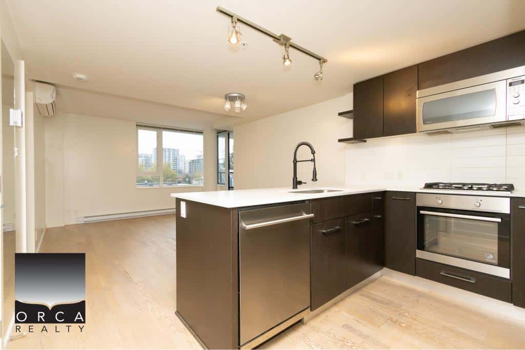 Modern open-concept kitchen with stainless steel appliances, dark wood cabinets, and a spacious white island, ideal for contemporary Vancouver or BC city living.