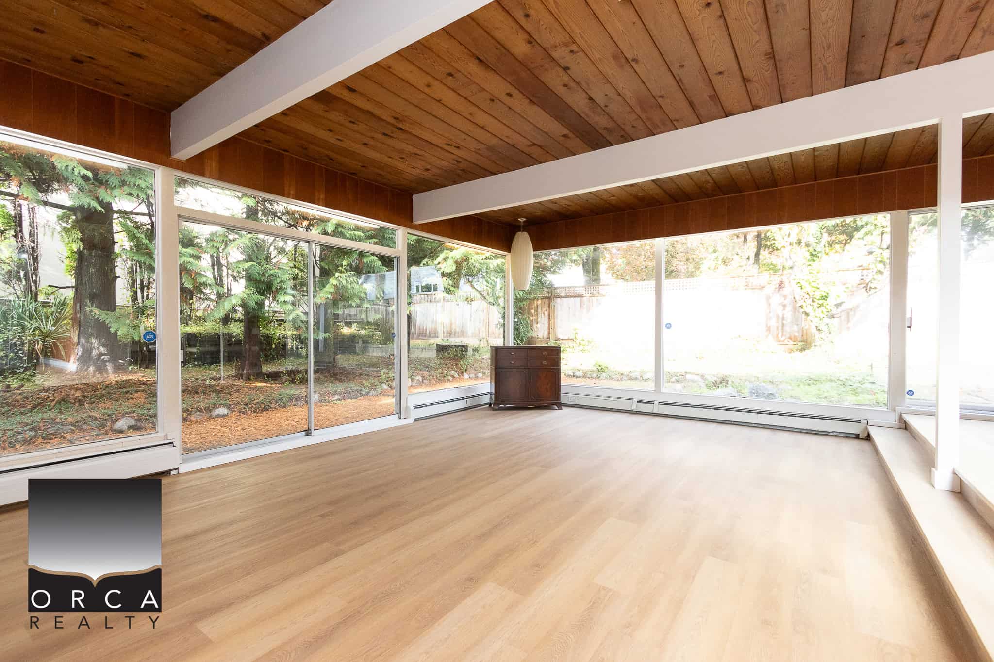 Bright sunroom with large glass windows overlooking lush backyard, ideal for relaxing or entertaining, featuring natural light and hardwood flooring, perfect for Vancouver area homes.