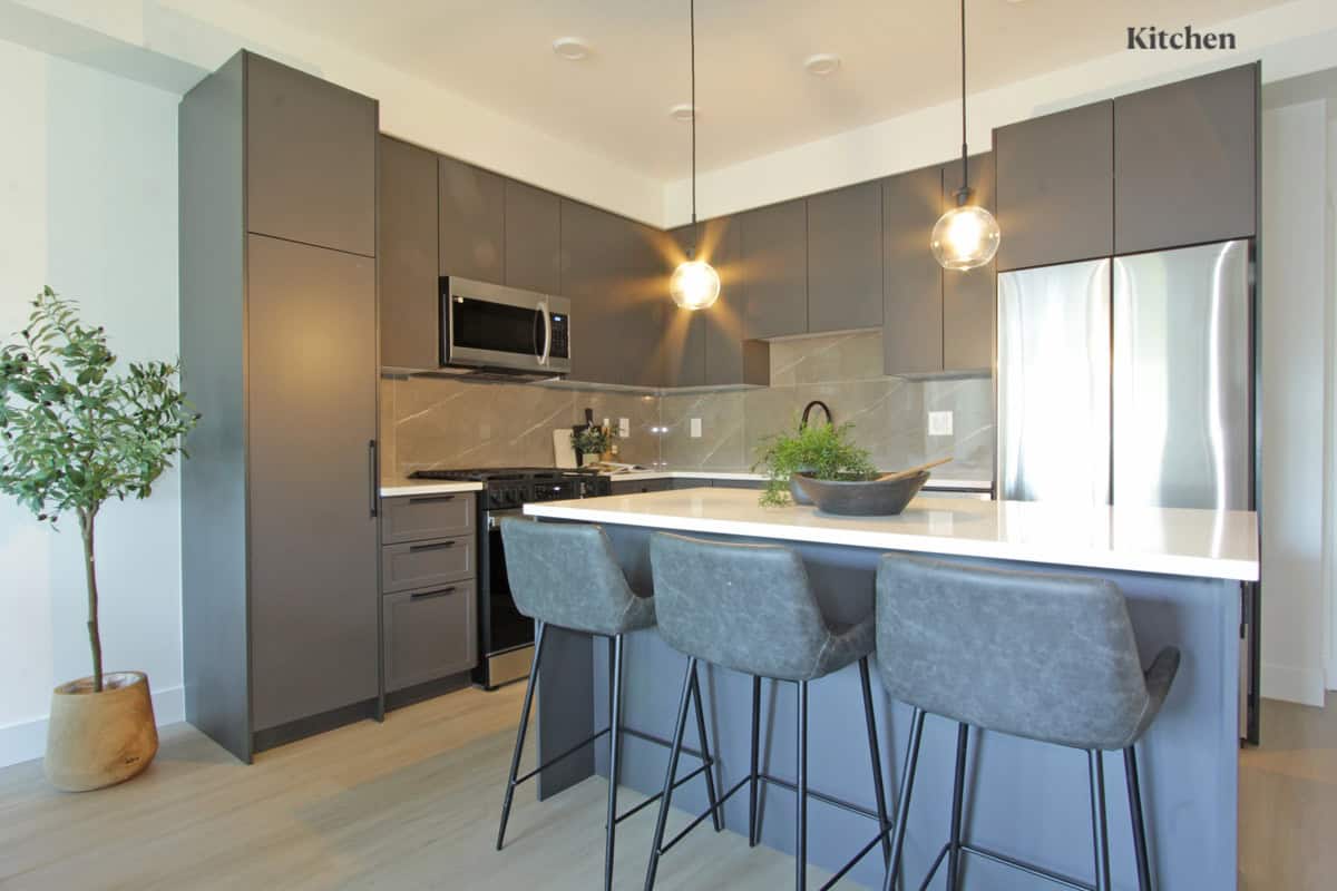 Modern grey kitchen with sleek cabinetry, stainless steel appliances, and a central island with bar stools, perfect for contemporary Vancouver Island home living.