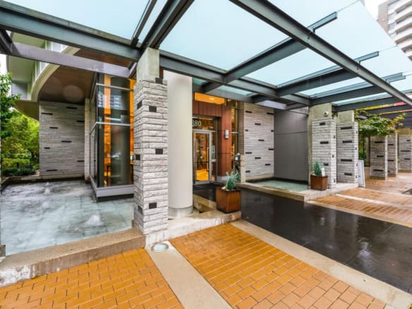 Luxury condo building entrance with modern architecture, water features, and landscaped greenery in Vancouver, BC. The building offers elegant design, upscale amenities, and a stylish urban lifestyle.